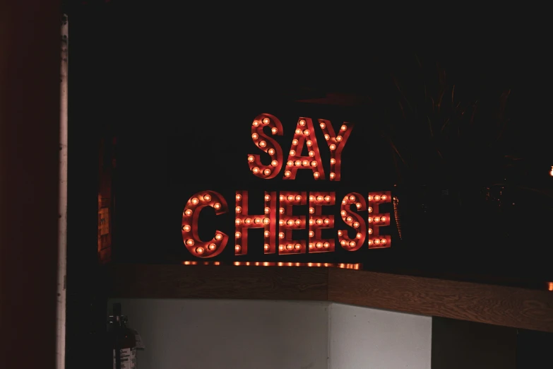 an advertising sign reading say cheese in the night