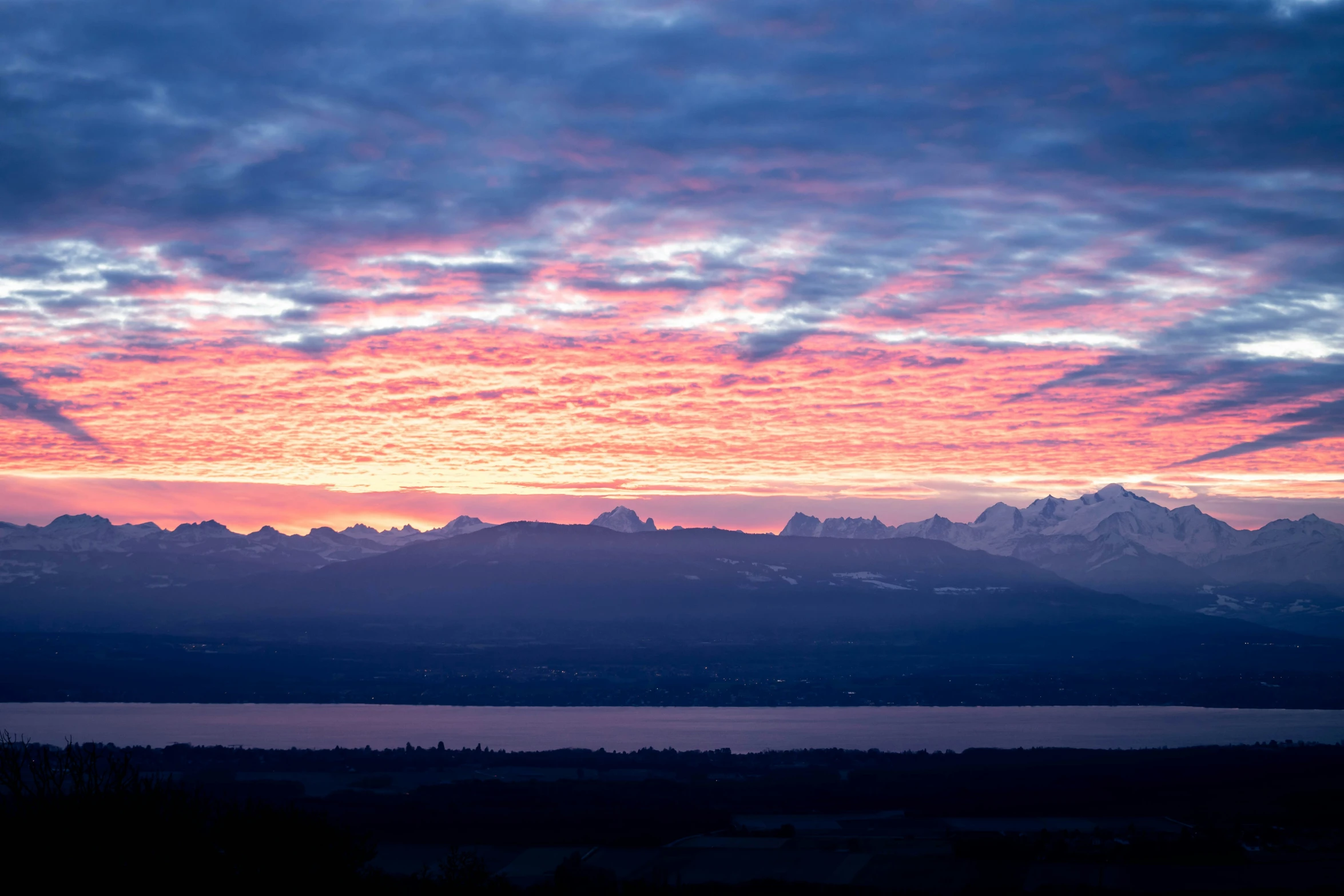 a pink sky is lit up over the mountains