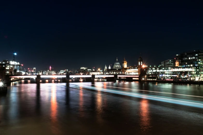 a bridge spanning a river at night with city lights