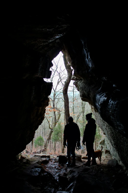 two people standing in a tunnel with a dog near by