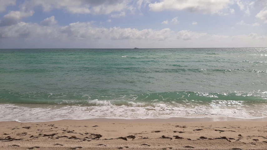 an empty beach with a boat on the horizon