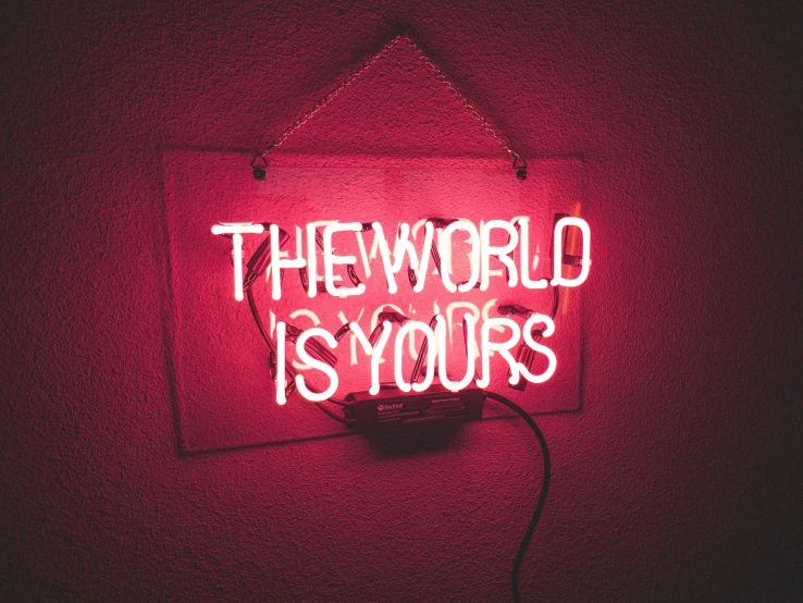 a red neon sign that reads the world is yours