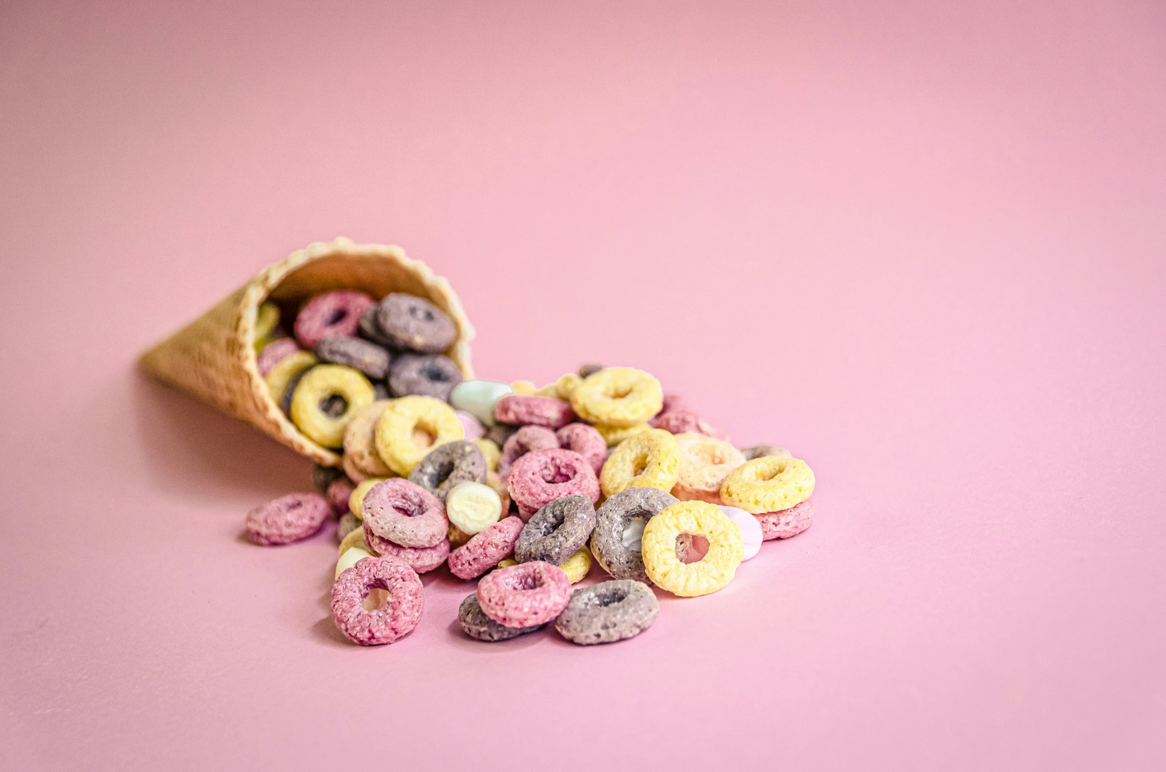 pink background with doughnuts in a bag with donuts on top