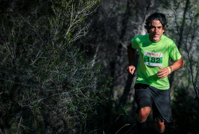 a man running on grass with a forest in the background