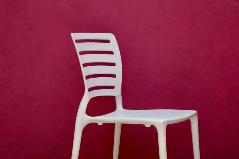 a white chair against a red wall in front of it