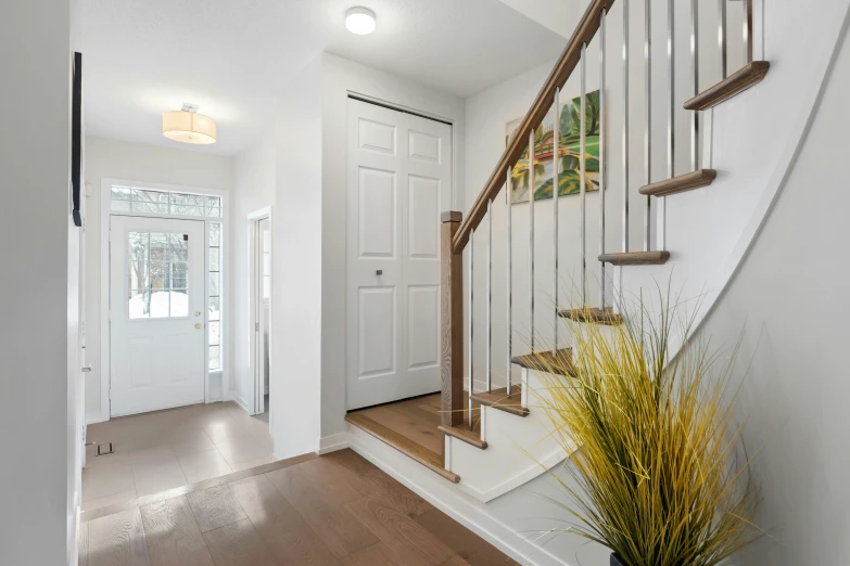 a beautiful entry with wood flooring, white walls and stairs