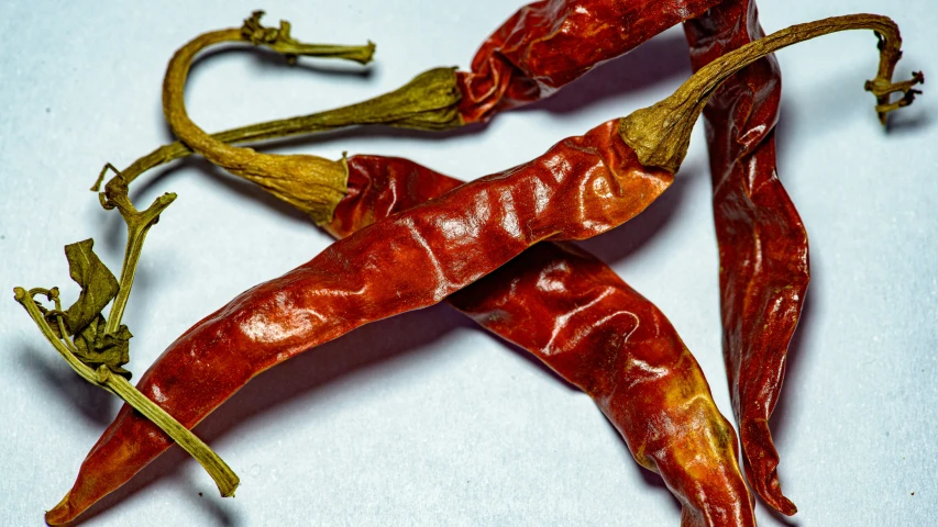 four small dried red peppers on a white table