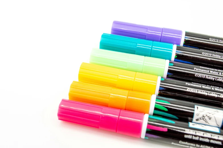 four color pens are stacked next to each other on a white surface