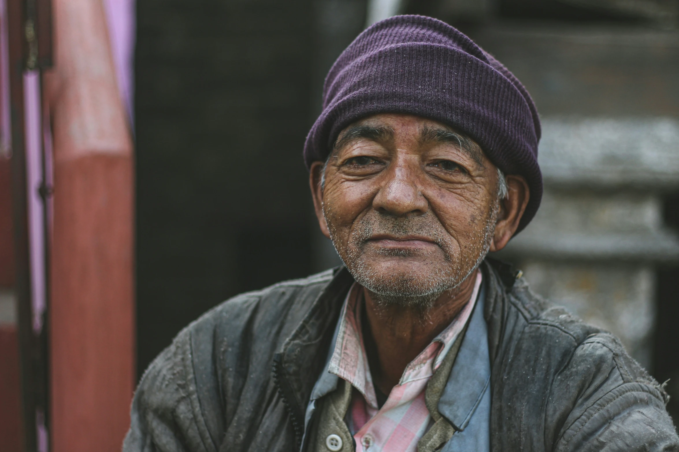 a older man is wearing a jacket and purple hat