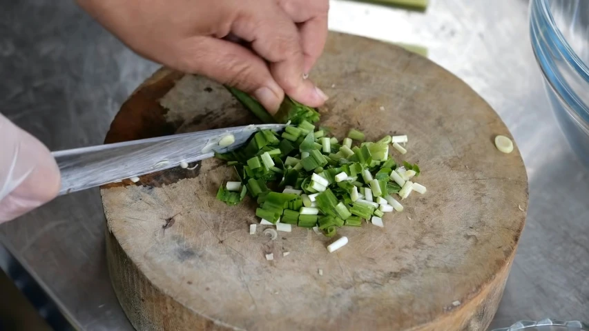 someone using their knife to chop the onions on the drum