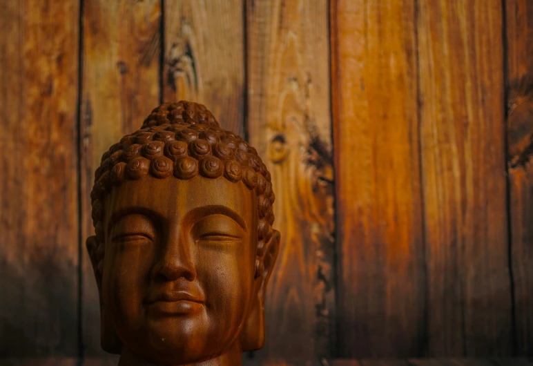 a close - up of a buddha statue on wooden surface