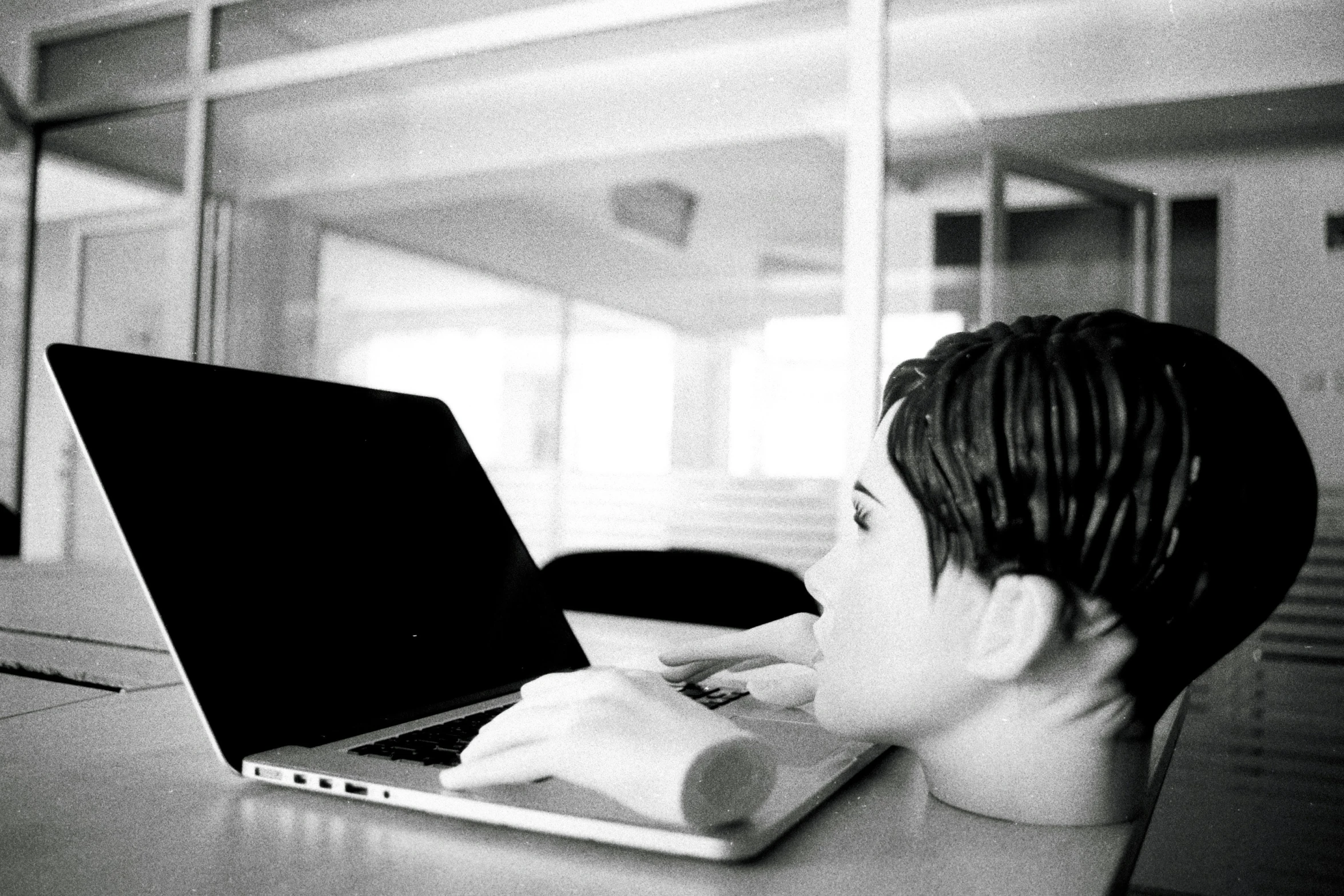 black and white po of boy on laptop looking at office window