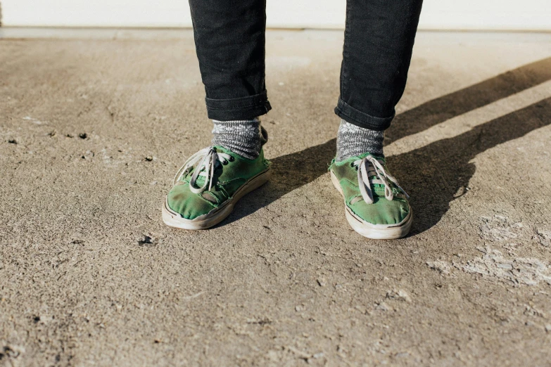 a man with green sneakers is standing on the ground