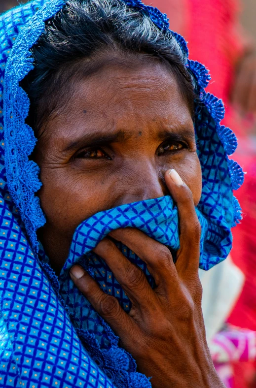 a woman with a blue head scarf covering her face