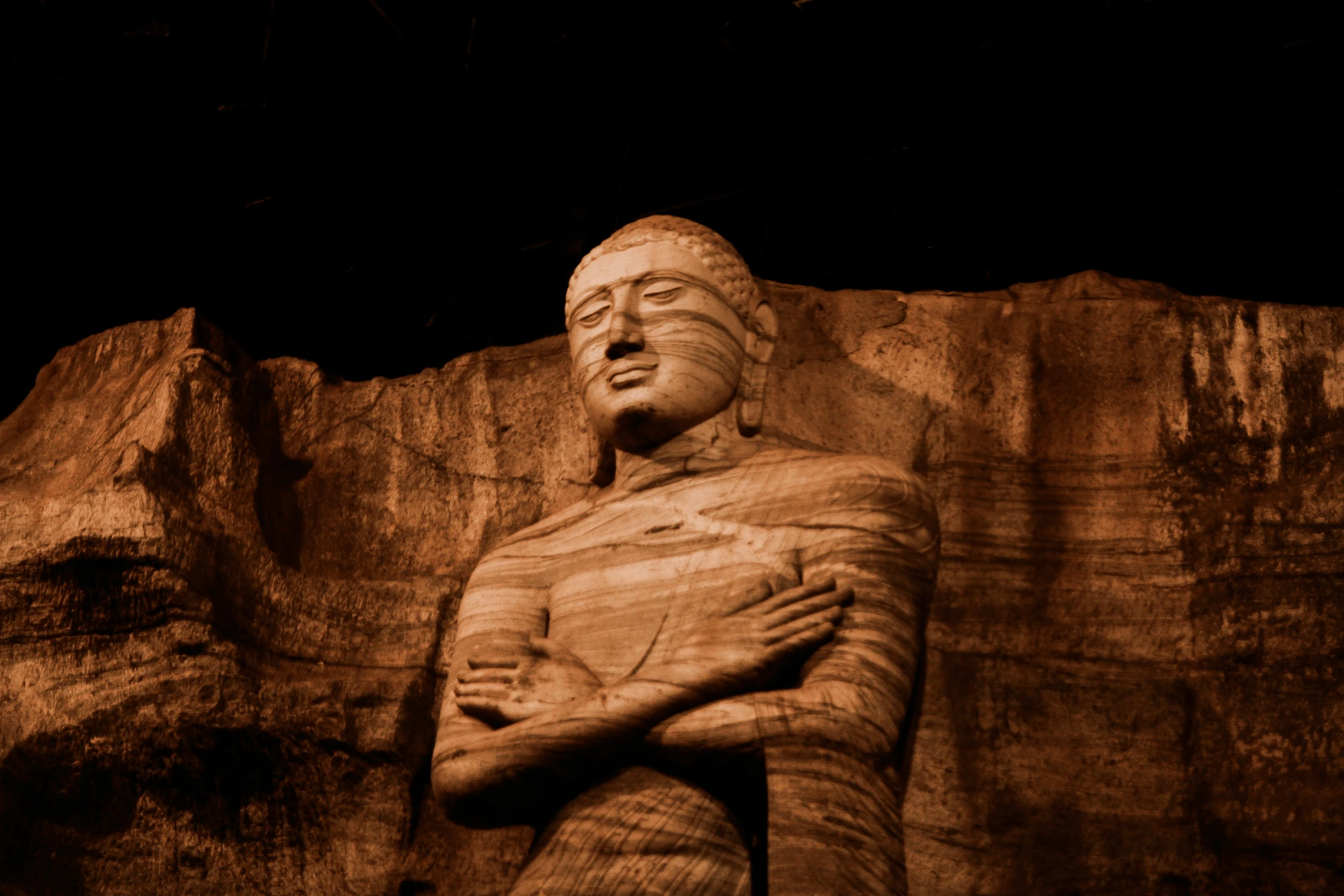 a brown statue of a man holding his arms crossed