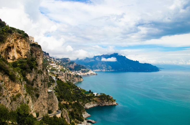 a blue sea and cliffs under cloudy skies