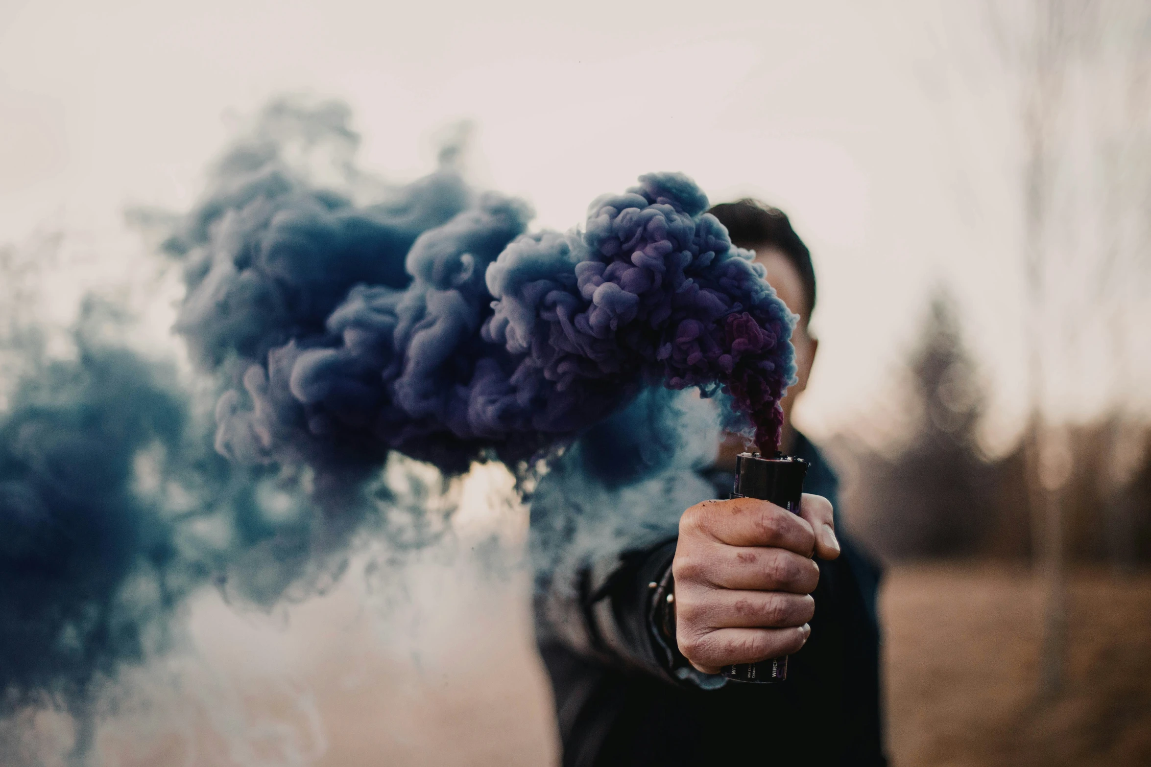 man in a black jacket holding a smoking stick