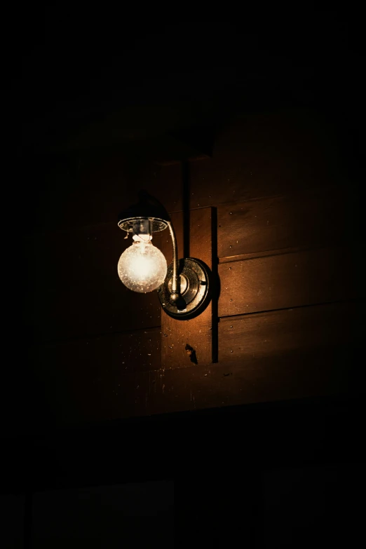 a light on the side of a dark wall with a door way sign