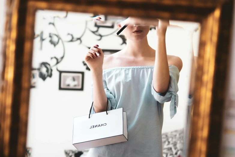 a woman holding a small bag in front of a mirror