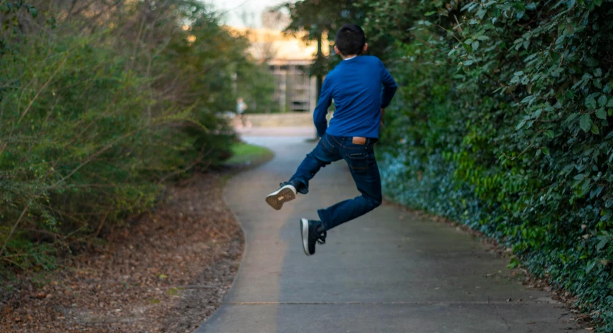 a boy in blue shirt doing a jump with skateboard