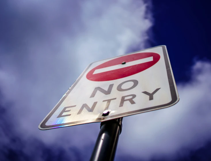 a street sign that reads no entry under a cloudy sky