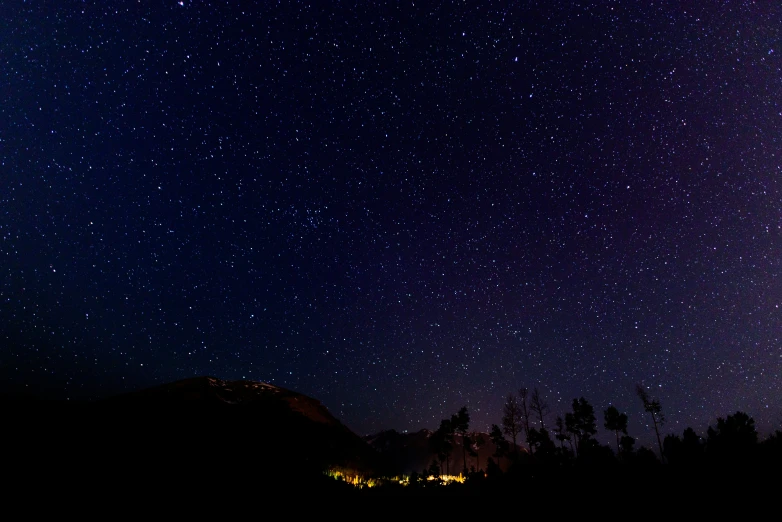 stars in the sky above trees and mountains