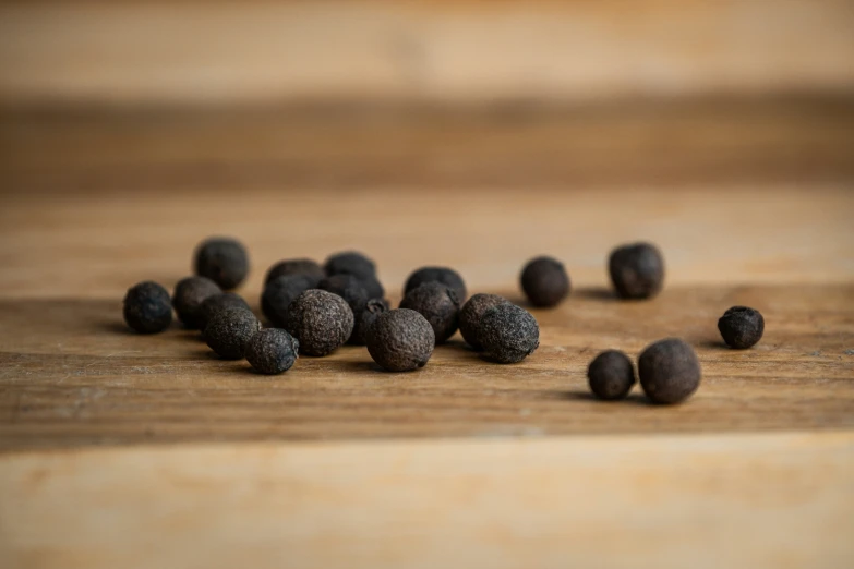 black pepper seeds on wooden surface scattered around