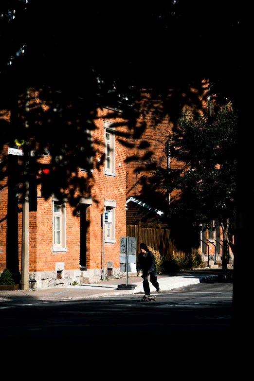 the silhouette of a man skateboarding on the street in front of an orange building