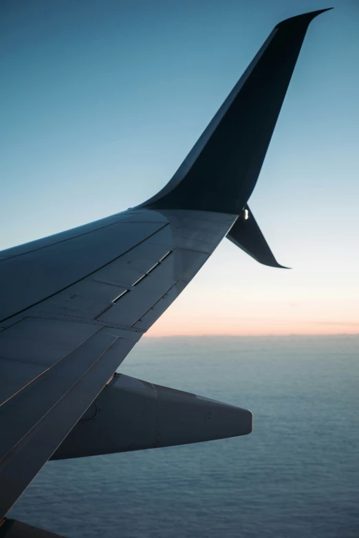 a view of an airplane wing looking down at the ocean