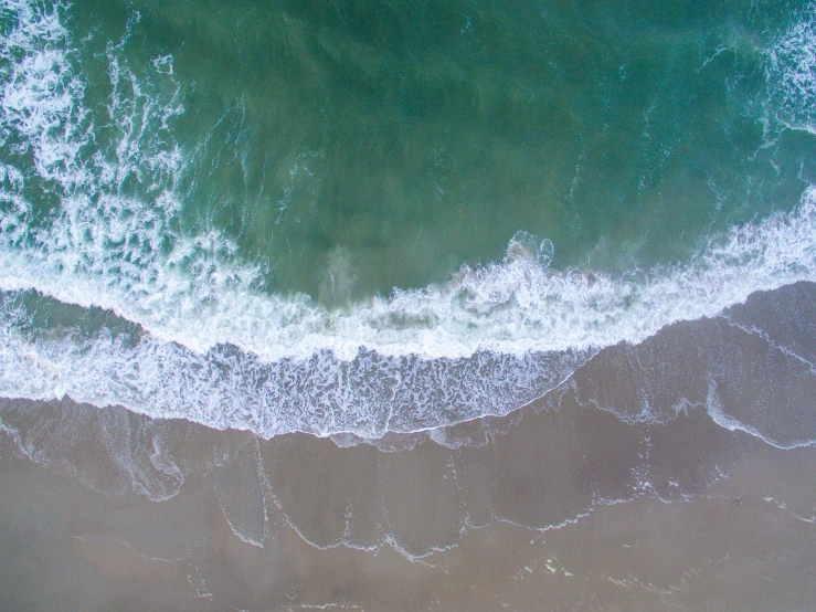 an aerial view of the ocean with white waves