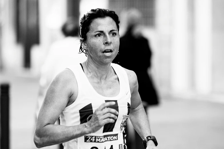 a woman in a marathon uniform running through a city