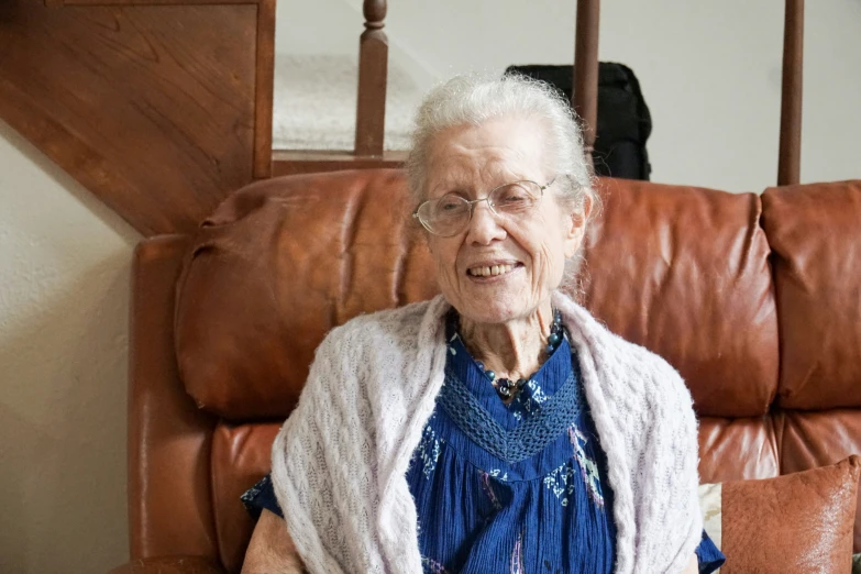 a smiling elderly woman sits in a chair