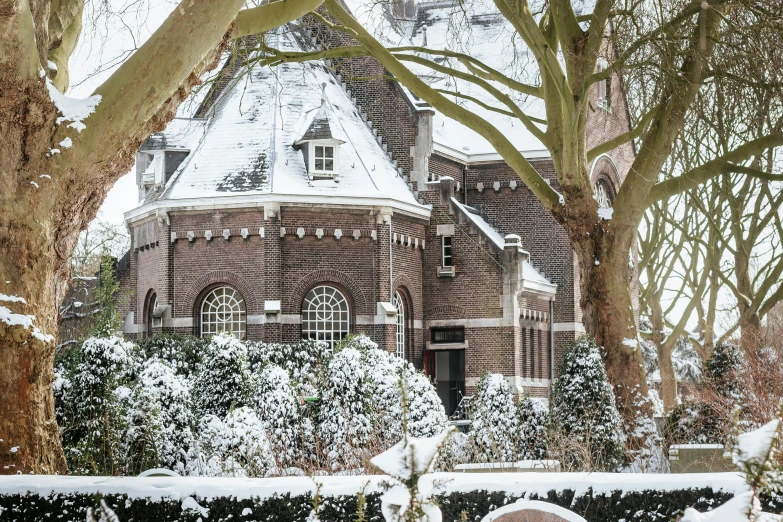 a red brick building in the snow with white trees and shrubbery