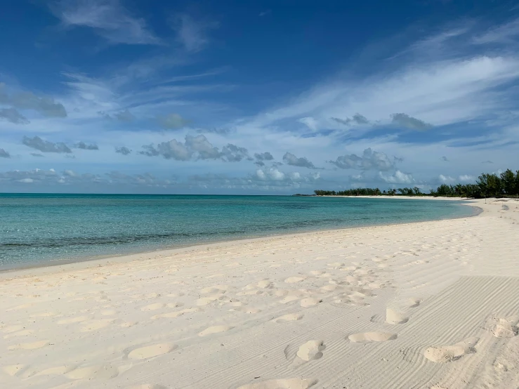 there is a clear and blue ocean with clouds in the sky