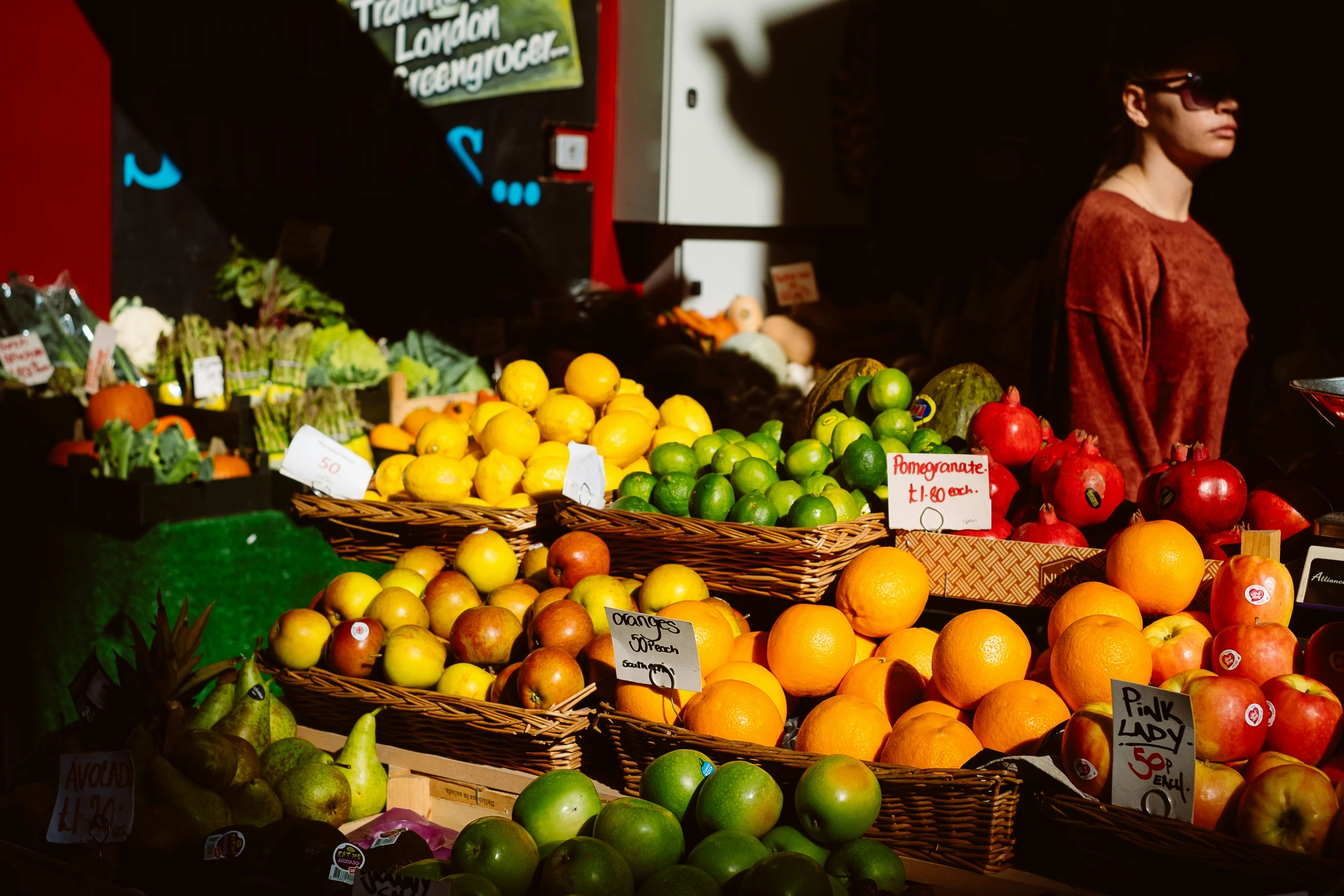 a fruit stand with fruits on display and people