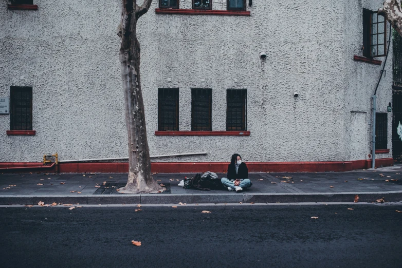 man sitting on the side of the road in front of a building