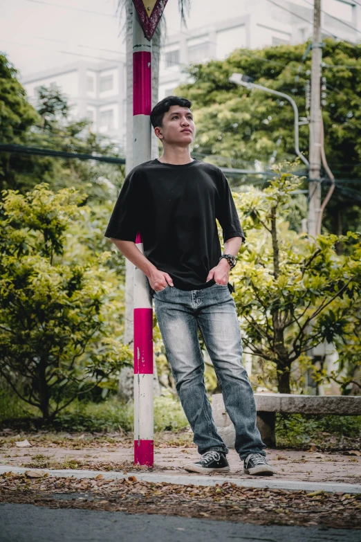 a man stands in front of a pole on a street