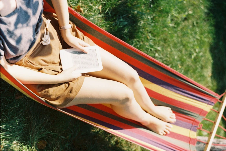 the woman is sitting down in the hammock reading