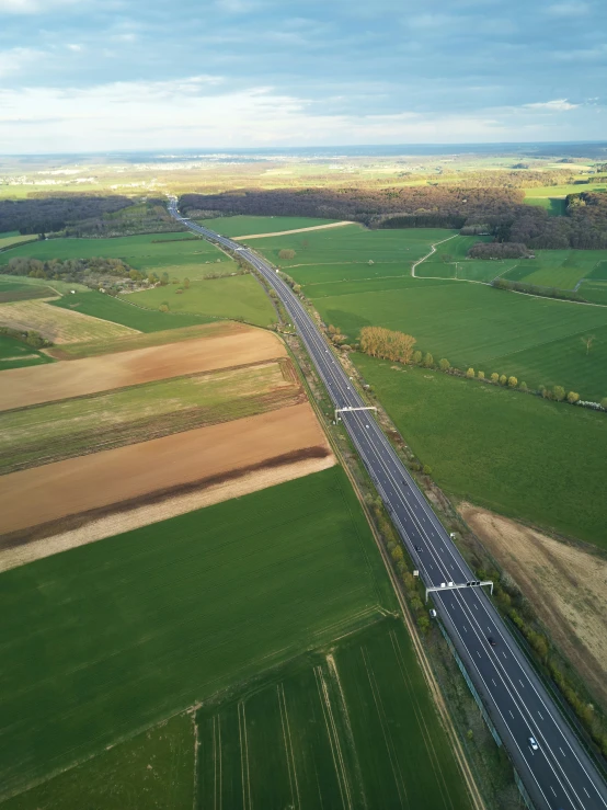 a very long highway surrounded by many different green fields