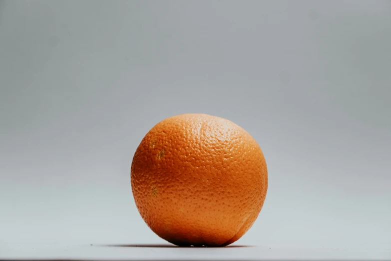 an orange is pographed against a gray background