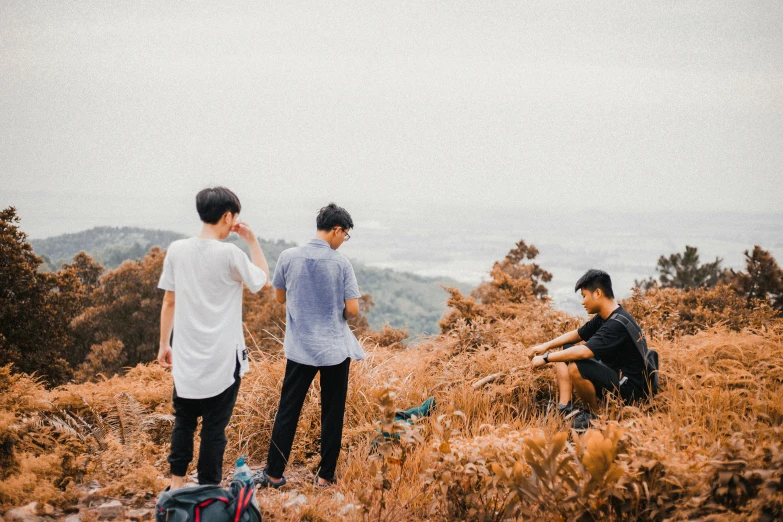 three people on the top of a mountain with one sitting
