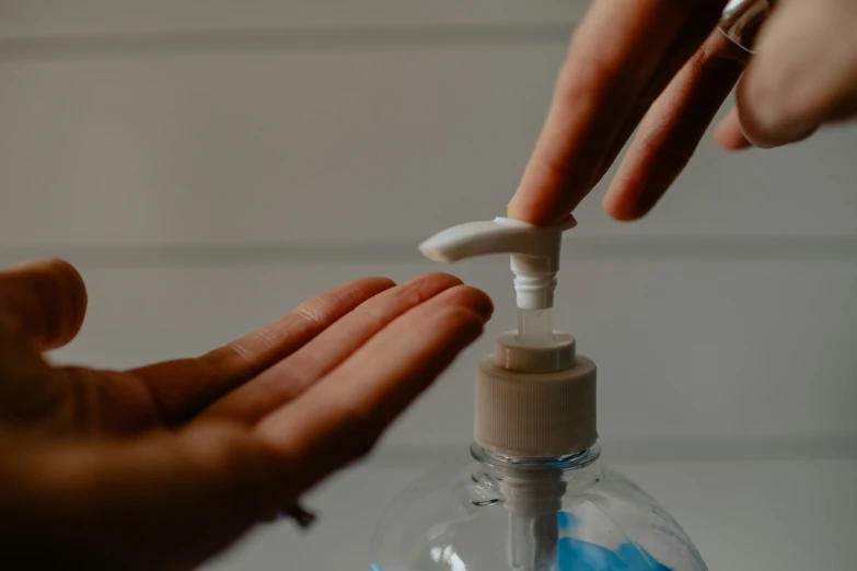 a person is applying disinfection to a small bottle of liquid
