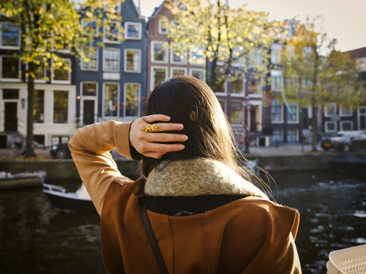 a woman with her back to the camera, standing next to a river