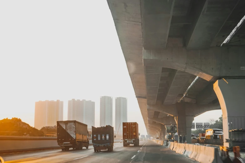 three trucks driving down a street with buildings in the background