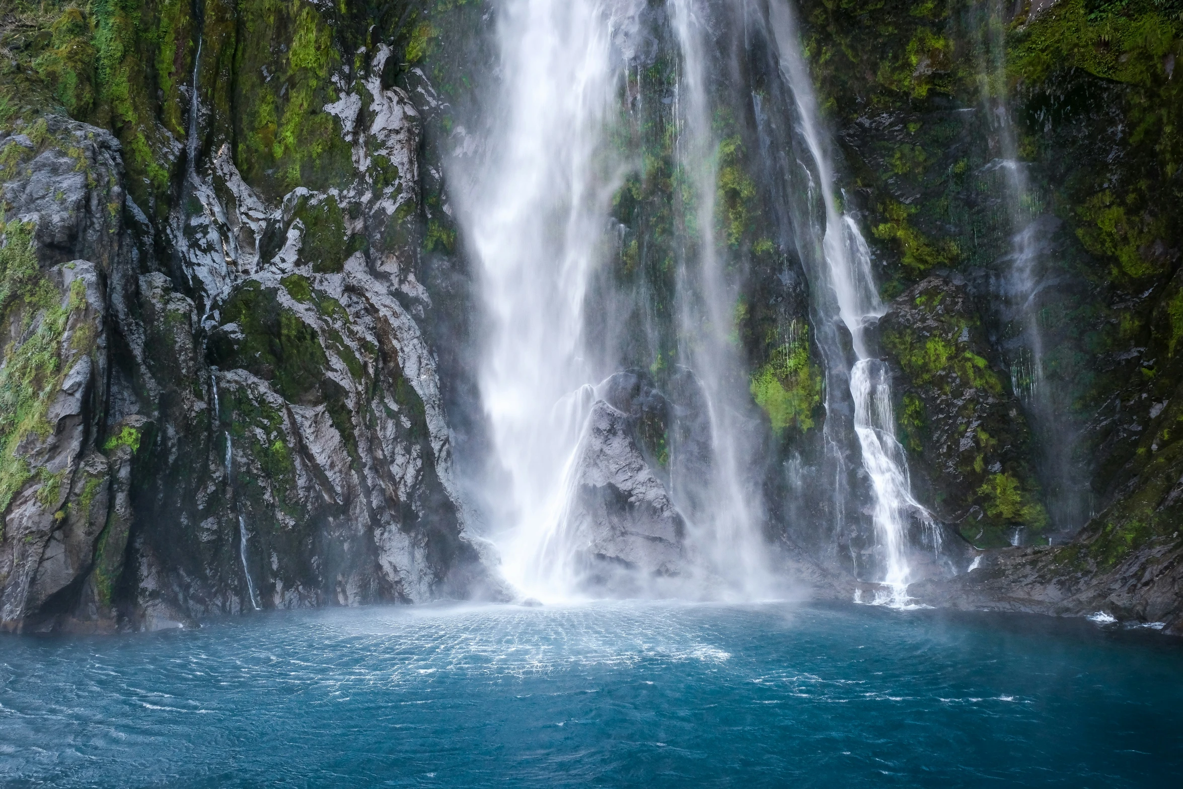 some water a huge waterfall and a lush green hillside