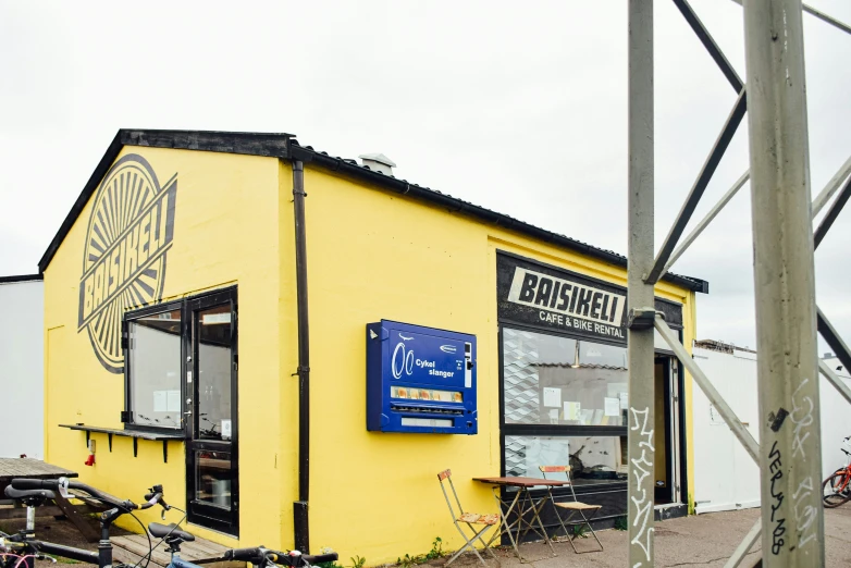 an old yellow store next to a tall metal object