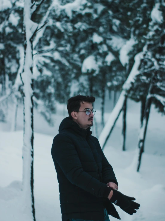 man with gloves on walking in snowy woods