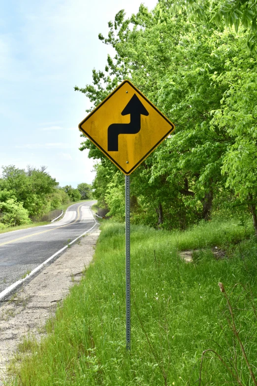 a yield sign for pedestrians on the roadside of a country road