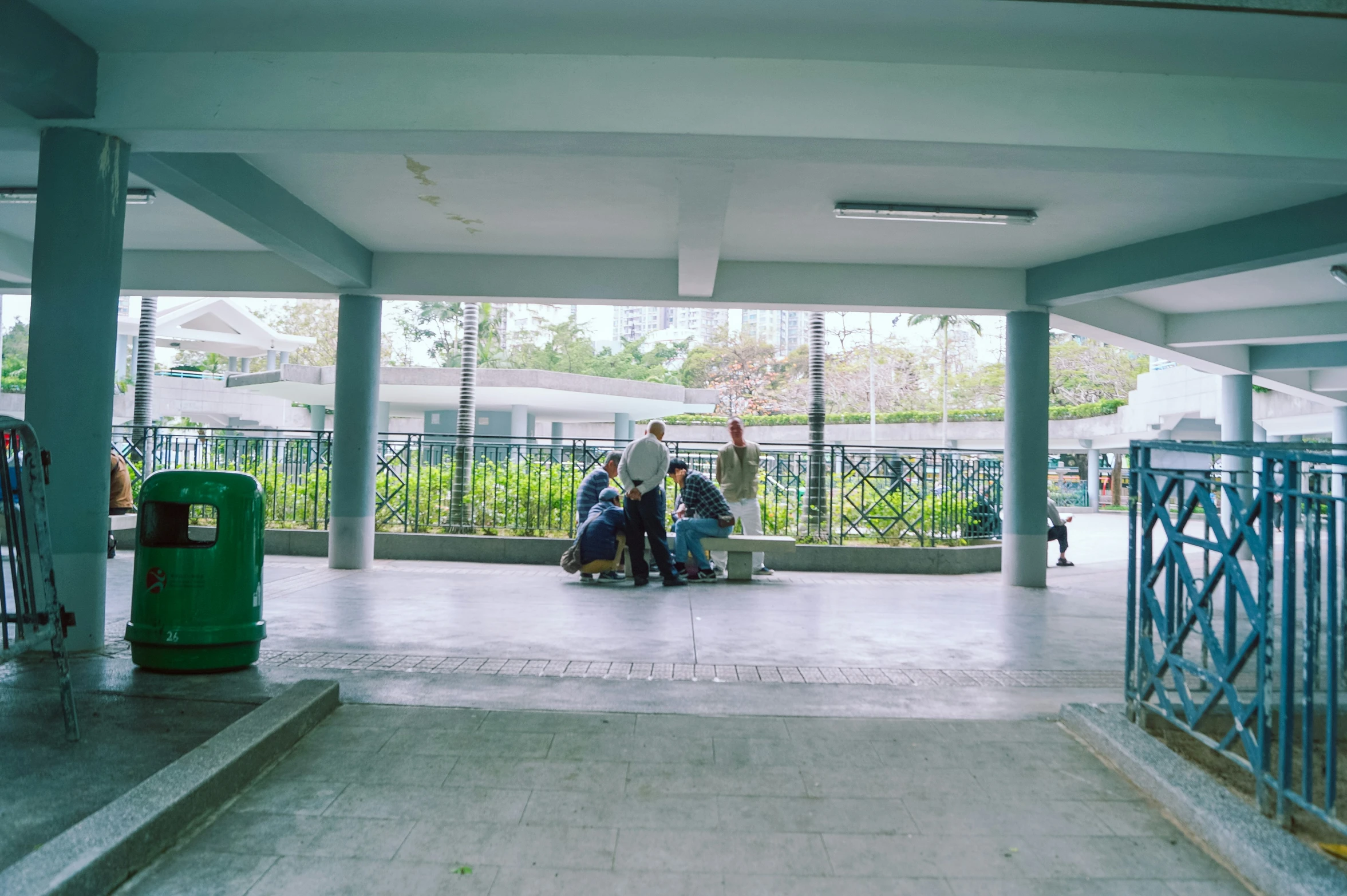 people walking down the walkway in front of a fenced in area