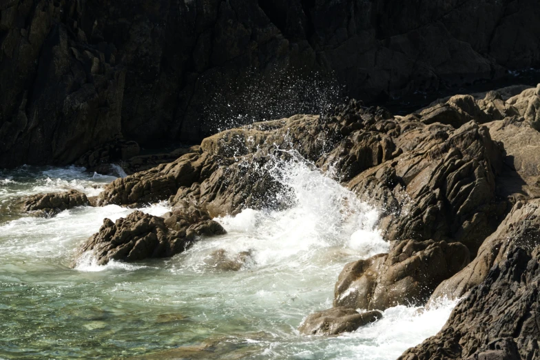 the water is splashing onto the rocky coastline